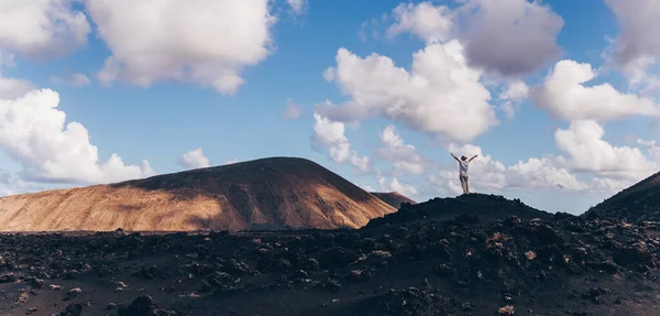 Kvinnan reser sig upp på himlen och njuter av fantastisk utsikt över det vulkaniska landskapet i nationalparken Timanfaya på Lanzarote i Spanien. Frihet och resor äventyr koncept. — Stockfoto