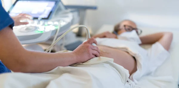 Närbild av en gravid kvinna som har ultraljudsundersökning på kliniken. Koncept för hälso- och sjukvård — Stockfoto