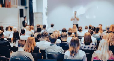 Sözcü, iş konferansında konferans salonunda konuşma yapacak. Konferans salonundaki tanınmayan insanların arka görüntüsü. İş ve girişimcilik kavramı.