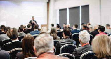 Sözcü, iş konferansında konferans salonunda konuşma yapacak. Konferans salonundaki tanınmayan insanların arka görüntüsü. İş ve girişimcilik kavramı
