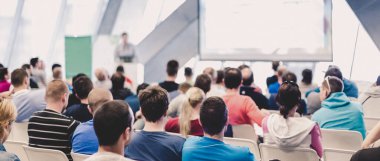 Konferans salonunda sunum yapan adam. Erkek konuşmacı halka açık bir etkinlikte konuşma yapıyor. Konferansı dinleyenler. Arka plan, seyircilere odaklan.