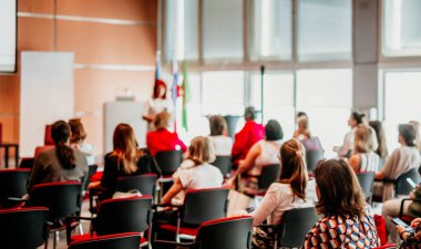 İş ve girişimcilik sempozyumu. İş toplantısında kadın konuşmacı bir konuşma yapıyor. Konferans salonunda dinleyiciler. İzleyicilerin tanınmayan katılımcılarının arka görünümü.