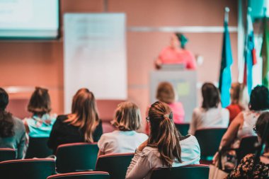 İş ve girişimcilik sempozyumu. İş toplantısında kadın konuşmacı bir konuşma yapıyor. Konferans salonunda dinleyiciler. İzleyicilerin tanınmayan katılımcılarının arka görünümü.
