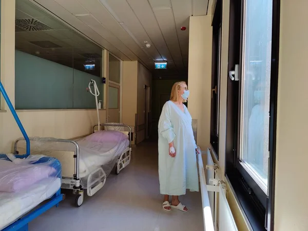 Solitary Female Patient Wearing Mask Hospital Robe Looking Out Trough — Stockfoto