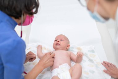 Onun doktoru onu bir standart tıbbi check-up sırasında inceler gibi onun arkasında yatan bebek.
