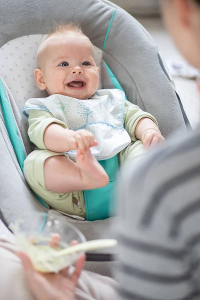 숟가락으로 가루를 의자에 아기에게 먹이고 있었다 스톡 이미지