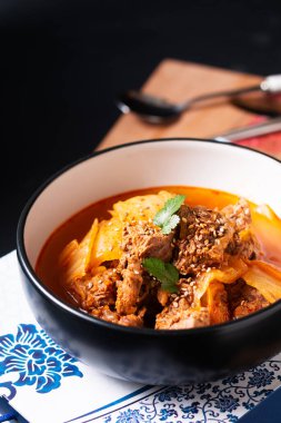 Asya Gıda Konsepti Baharatlı Biftek ve Kimchi Çorbası veya Kimchi Jjigae siyah seramik kasede fotokopi alanı ile ahşap tahtada