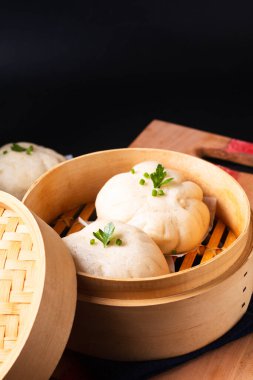 Çin yemeği kavramı Çin hamur köftesi Baozi Dim Sum bambu budan buharlı tahta tahta tahta üzerinde siyah taş zemin üzerinde fotokopi alanı 