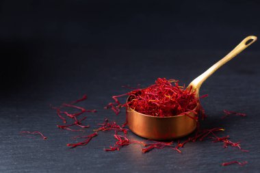 Food ingredient spice concept Saffron crocus spice in copper cup on black background with copy space