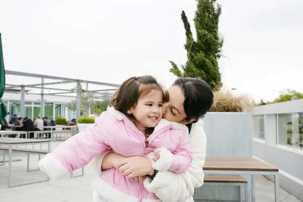 Menina feliz recebendo um beijo de sua mãe — Fotografia de Stock