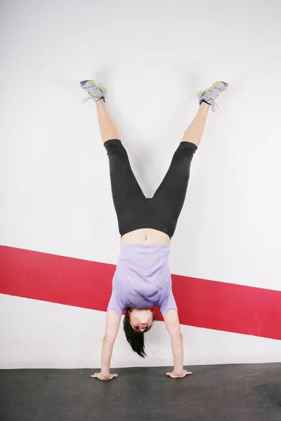 Brunette handstand woman isolated on gym — Stock Photo, Image