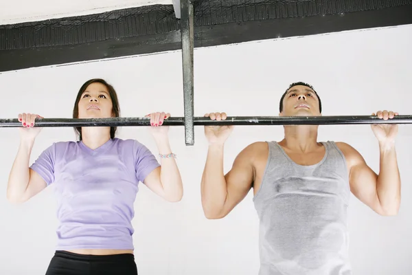 Young adult fitness woman and man preparing to do pull ups in pu — Stock Photo, Image