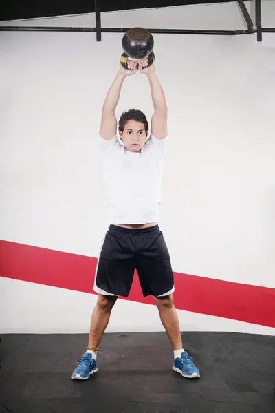 Joven haciendo entrenamiento de Kettlebell en el gimnasio —  Fotos de Stock