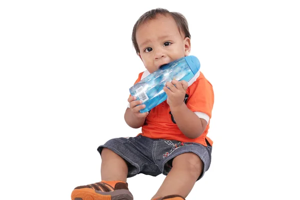 Entzückendes einjähriges Kind beißt Flasche und lächelt, isoliert — Stockfoto