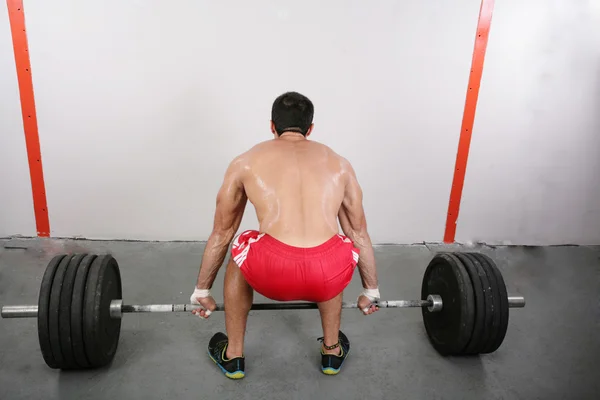 O homem faz exercícios do aumento na força de músculos. Foco em — Fotografia de Stock