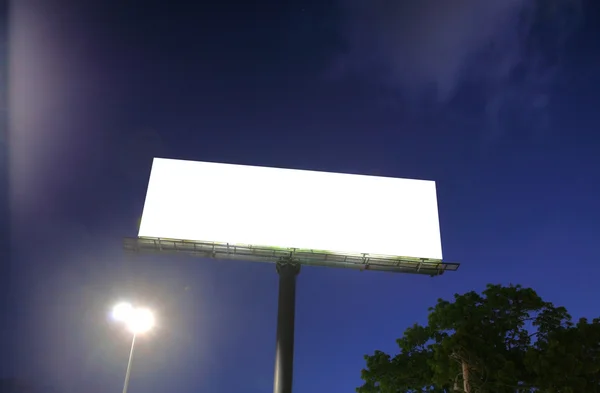 Leeg reclamebord in een blauwe lucht en groene boom als achtergrond — Stockfoto