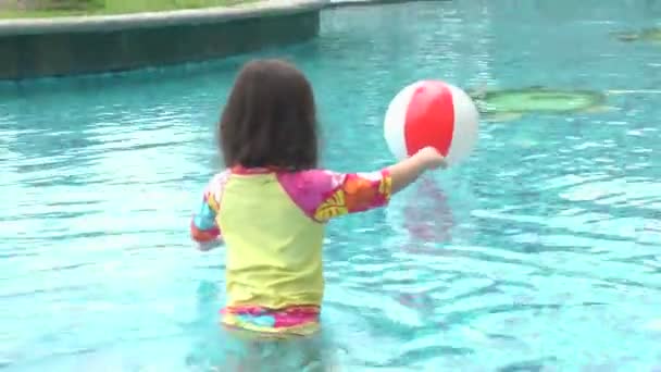 Klein meisje spelen met een kleurrijke bal in het zwembad — Stockvideo