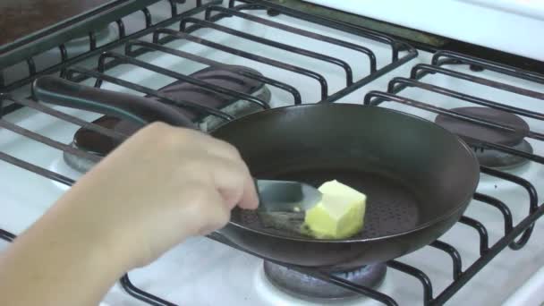 Um botão de manteiga é colocado em uma frigideira quente e derrete . — Vídeo de Stock