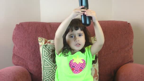Kleines Mädchen versucht, mit Fernbedienung die Kanäle im Fernsehen zu wechseln — Stockvideo