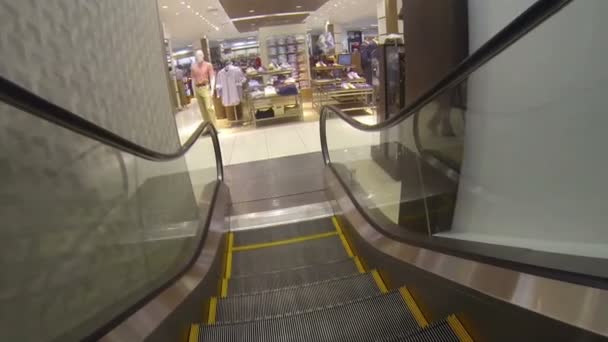 Centro comercial montar por escaleras mecánicas a la zona de ropa — Vídeo de stock