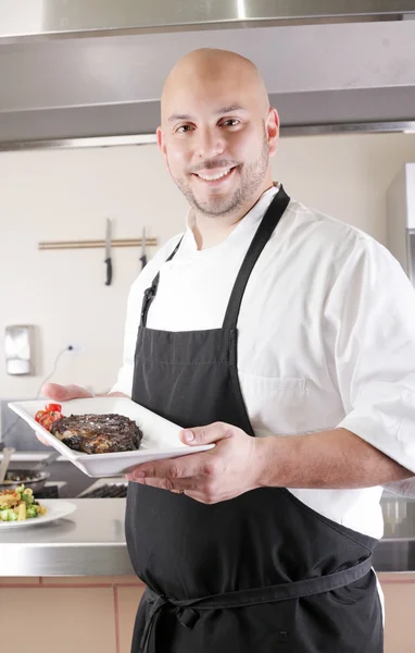 Chef presenting a juicy steak in the kitchen — Stock Photo, Image