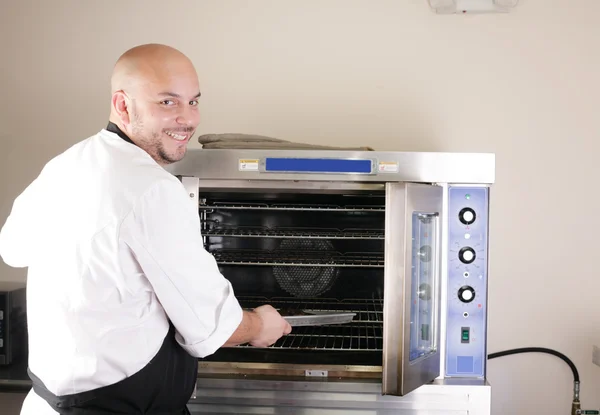 Happy young chef cooking steak in the oven — Stock Photo, Image