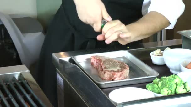 Шеф-повар солит стейк из ребрышек перед готовкой — стоковое видео
