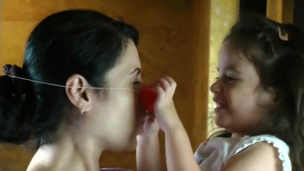 Silly girl puts clown nose on mother — Stock Video