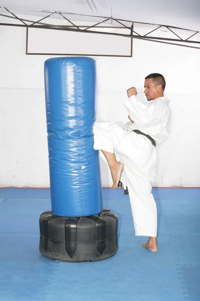 Athletic black belt karate giving a forceful knee kick during a — Stock Photo, Image
