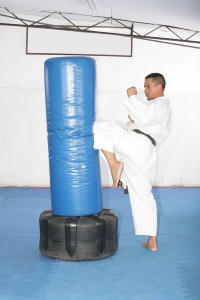 Atletico cinturón negro de karate dando una patada de rodilla fuerte durante un — Foto de Stock