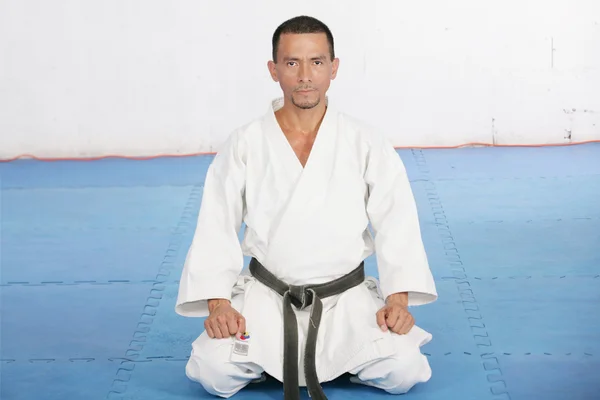 Black Belt uomo karate sedersi su una posizione per iniziare o finire pract — Foto Stock