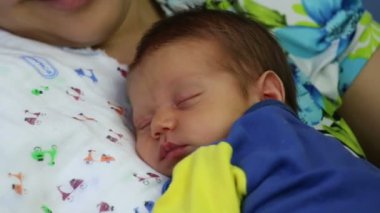 Annenin kollarında uyuyan bebek