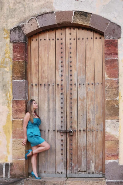 Young woman in long dress standing in front an old door.  Focus — Stock Photo, Image