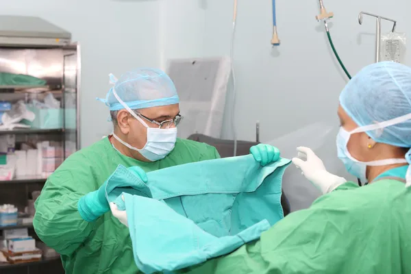 Médico y asistente doblando la manta para la cirugía — Foto de Stock