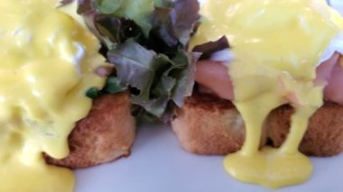 Benedict yumurtasıyla nefis bir kahvaltı. Haşlanmış yumurta yayılıyor. Kahvaltı tabağı. Tost, somon ve ıspanak üzerine yumurta duası..