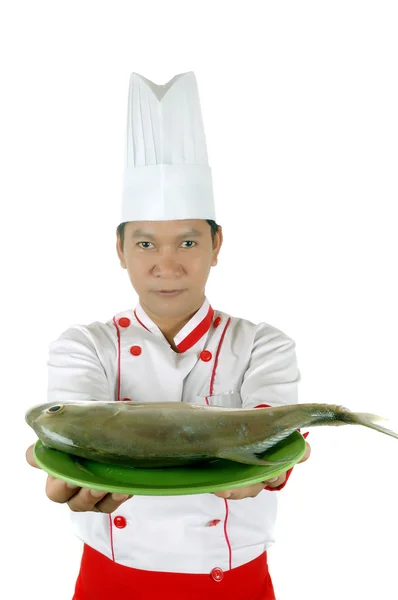 Kocken håller rå fisk på en grön platta — Stockfoto