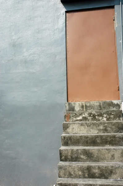 茶色の金属製のドアにつながる具体的な階段 ロイヤリティフリーのストック写真