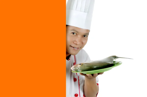 Chef sosteniendo pescado crudo en un plato verde con espacio en blanco naranja —  Fotos de Stock