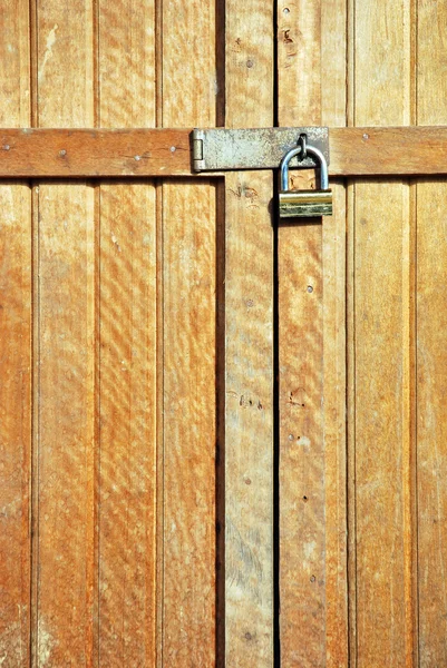 Porta de madeira trancada com um cadeado dourado — Fotografia de Stock