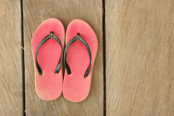 Red used flip-flops on wooden board — Stock Photo, Image