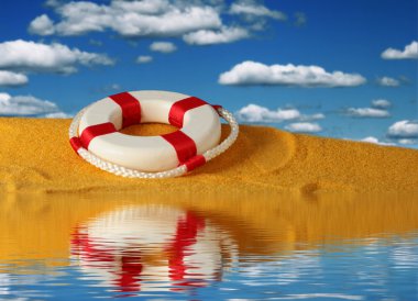 Lifebuoy gökyüzü arka plan üzerinde sarı kum üzerinde.