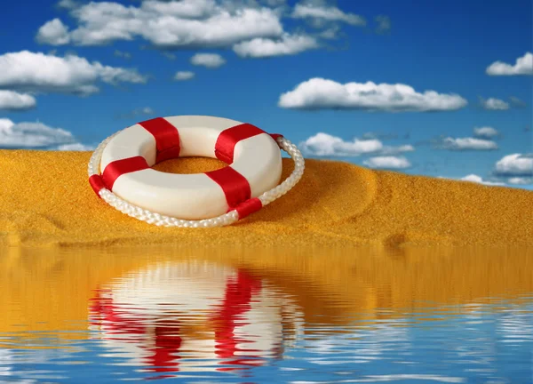 Livboj på gul sand över himmel bakgrund. — Stockfoto