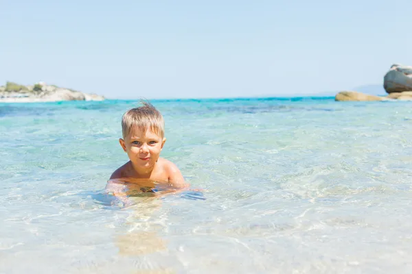 Rapaz bonito brincando no mar — Fotografia de Stock