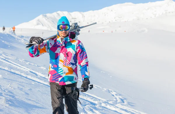 Junger Mann mit Skiern und Skibekleidung — Stockfoto