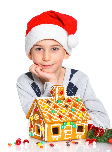 Menino de chapéu de Pai Natal com casa de gengibre — Fotografia de Stock