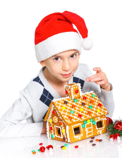 Little boy in Santa's hat with gingerbread house — Stock Photo, Image