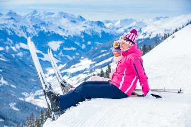 Young skier sitting on the hill clipart