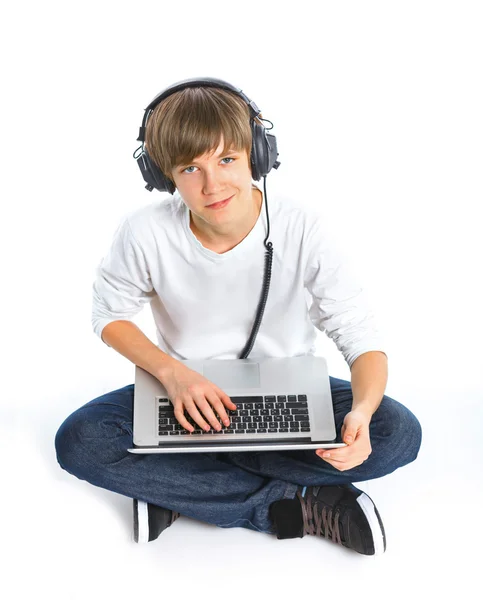 男孩戴着耳机坐在一台笔记本电脑 — 图库照片