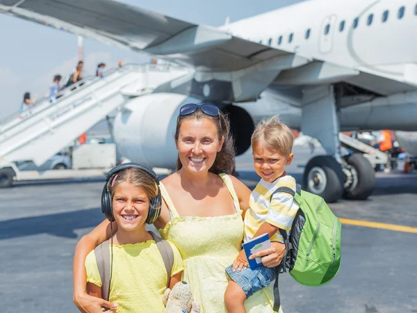 Młoda matka z dwójką dzieci przed samolotem — Zdjęcie stockowe