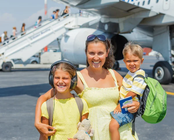 Jovem mãe com dois filhos na frente do avião — Fotografia de Stock